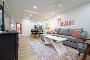 Ein modernes Wohnzimmer mit einem grauen Sofa, einem weißen Couchtisch und einem Fernseher auf einem schwarzen Schrank.