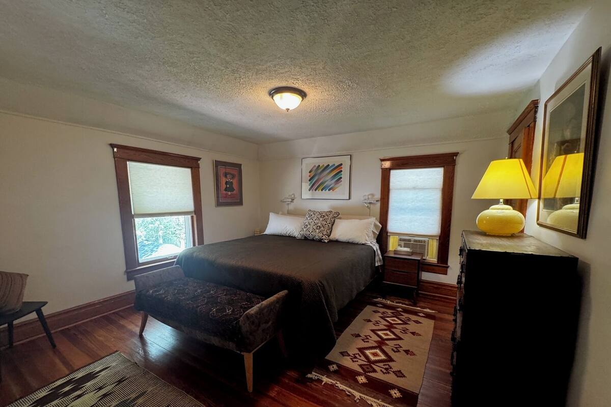 Ein Schlafzimmer mit einem Bett, einem Sessel, einer Lampe und einem Teppich.