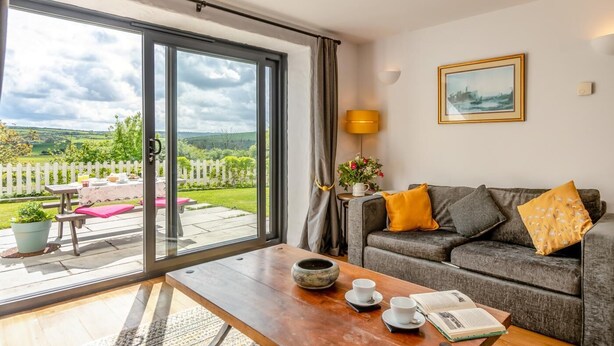 A living room with a sofa, a coffee table, and a view of a garden through a sliding glass door. - 2 Bed in Dwrbach (oc-w42727) (Dwrbach)