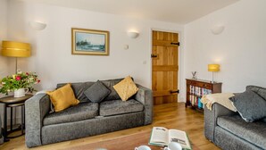 A living room with a grey sofa, a wooden door, a bookshelf, and a lamp. - 2 Bed in Dwrbach (oc-w42727) (Dwrbach)