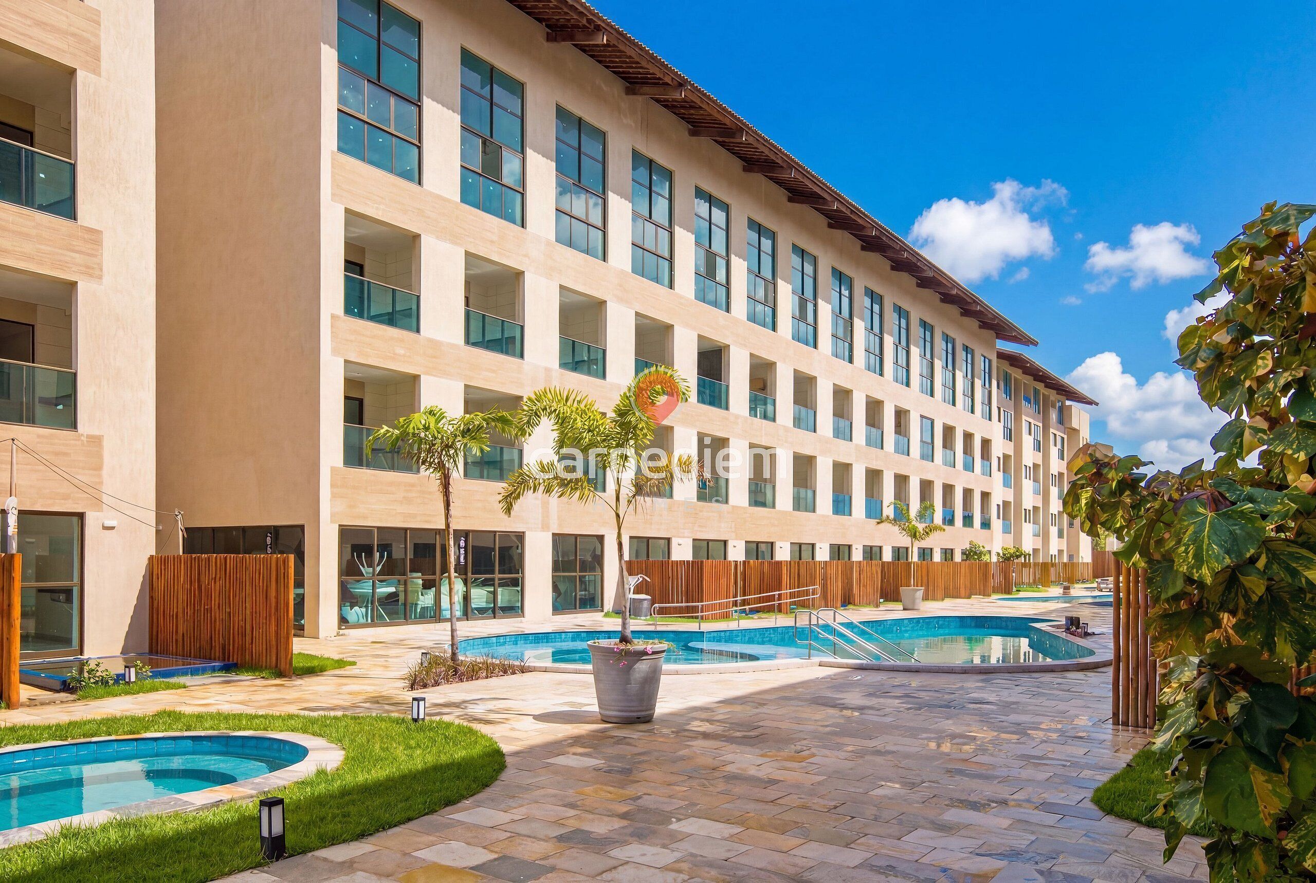 Um hotel com piscina, área de estar externa e um edifício grande com várias janelas.