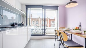A modern kitchen with a dining area, large windows, and a view of the city. - 2 Bed in Swanage (oc-c41747) (Swanage)