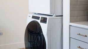 A stacked washer and dryer unit in a modern kitchen with a light-colored wall and a wooden floor. - Be A Nomad | New Listing l 2br 3 blks to beach - D (Jacksonville Beach)