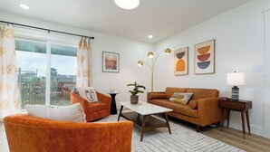 A living room with a sofa, armchair, coffee table, and a lamp. - Be A Nomad | New Listing l 2br 3 blks to beach - D (Jacksonville Beach)