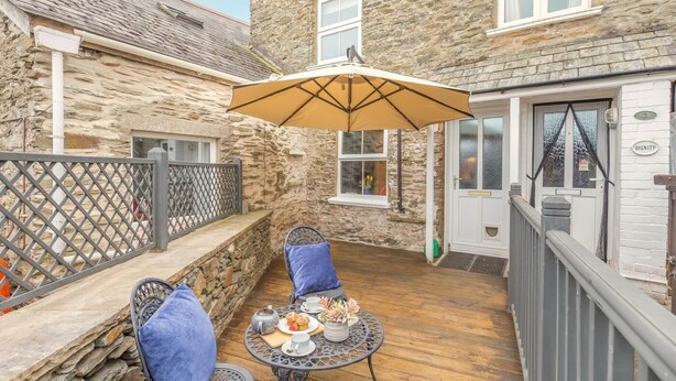 A stone house with a patio, a table with chairs, and a covered area with an umbrella. - 2 Bed in Lynton (oc-v42649) (Lynmouth)