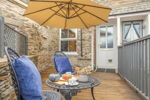 Eine Terrasse mit Tisch, Stühlen und Sonnenschirm.