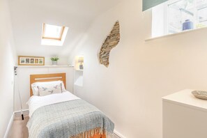 A bedroom with a bed, a skylight, a stone wall, a bedside table, and a window. - 2 Bed in Lynton (oc-v42649) (Lynmouth)