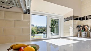 A kitchen with a white countertop, a bowl of fruit, and a view through a sliding glass door.