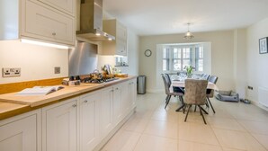 A modern kitchen with a central island, dining table, and chairs. - 4 Bed in Mundesley (oc-s42724) (Mundesley)