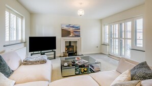 A living room with a flat-screen TV, a fireplace, and a sofa. - 4 Bed in Mundesley (oc-s42724) (Mundesley)