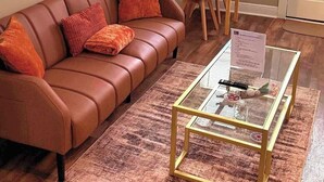 Un salon avec un canapé en cuir marron, une table basse en verre et une table à manger avec des chaises.