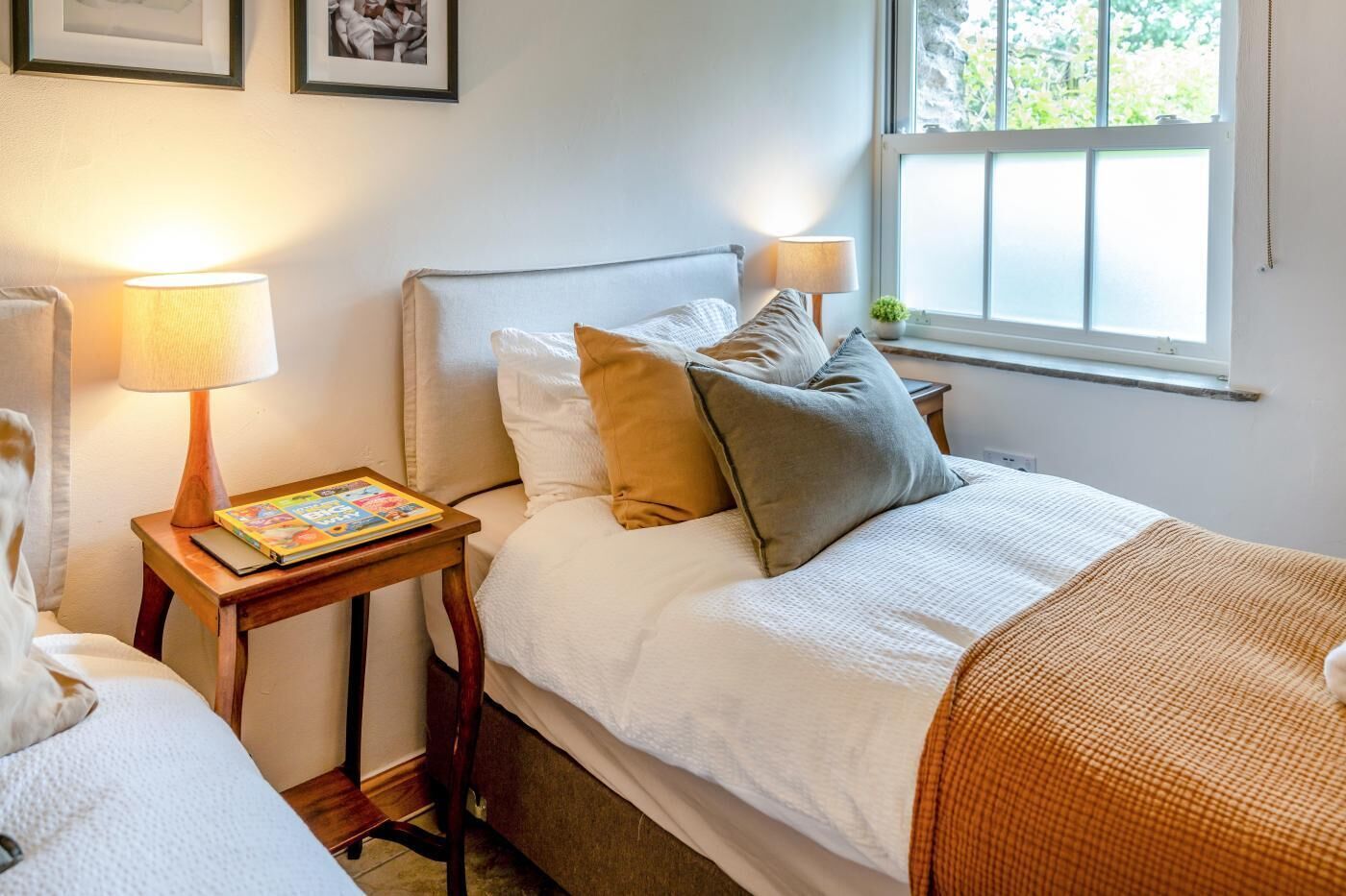 A bedroom with a bed, two bedside tables, a window, and a lamp.