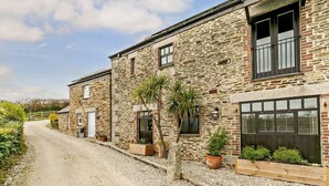 A stone building with a gravel driveway, wooden fences, and potted plants. - 3 Bed in Duloe (oc-h27526) (Duloe)