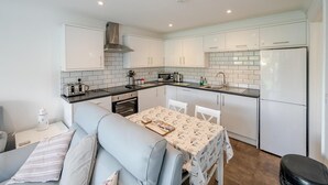 Una cocina compacta con gabinetes blancos, horno empotrado, microondas y refrigerador.