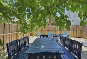 A wooden deck with a table and chairs, surrounded by a wooden fence and greenery. - Be A Nomad | 4BR Ocean View House | 1 Block to Jacksonville Beach | Sleeps 7 (Jacksonville Beach)