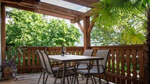 A wooden deck with a table and chairs, surrounded by a wooden fence, and a view of lush greenery. - Saxöler – Cozy Apartment in Historic Winery near Brixen (Brixen)
