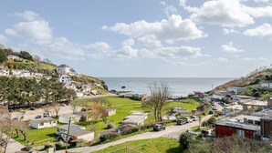 Une zone résidentielle côtière avec des maisons, un ciel dégagé et la mer en arrière-plan.