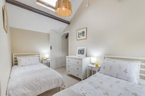 A bedroom with two beds, a dresser, bedside tables with lamps, a hanging light fixture, and a framed picture on the wall. - 2 Bed in Llangynidr (oc-b42697) (Llangynidr)