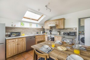 A modern kitchen with wooden cabinets, a dining table set for four, and a skylight above. - 2 Bed in Llangynidr (oc-b42697) (Llangynidr)