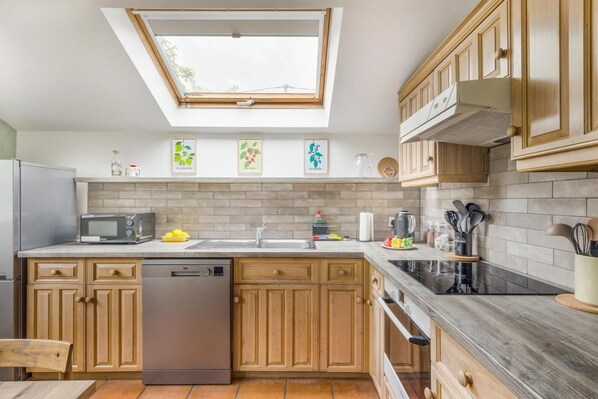 A kitchen with wooden cabinets, a dishwasher, a microwave, and a skylight. - 2 Bed in Llangynidr (oc-b42697) (Llangynidr)