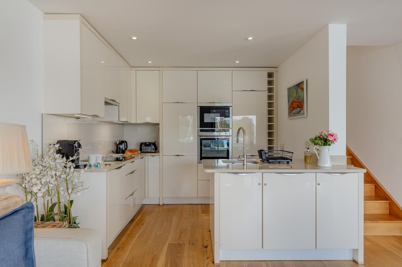 A modern kitchen with white cabinetry, a built-in oven, and a sink.