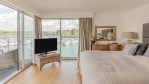 Hotelkamer met balkon, televisie, bed, bureau en uitzicht op de jachthaven.