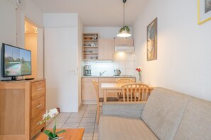 A compact living space with a kitchenette, a dining area, a sofa, a TV, and a plant. - Attraktive Ferienwohnung mit Balkon Ostseenah in Sellin (Sellin)