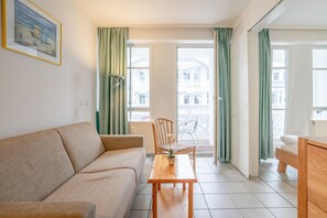 Ein Zimmer mit einer Couch, einem Holztisch mit Topfpflanze, einem Sessel und einem Bett.