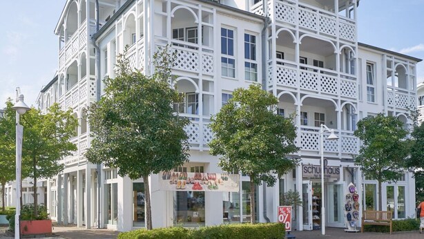 A multi-story building with balconies, a shop on the ground floor, and a sign indicating a sale. - Attraktive Ferienwohnung mit Balkon Ostseenah in Sellin (Sellin)
