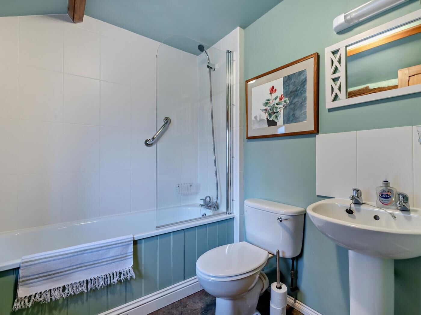 Une salle de bain avec une baignoire, des toilettes, un lavabo et un tableau encadré au mur.