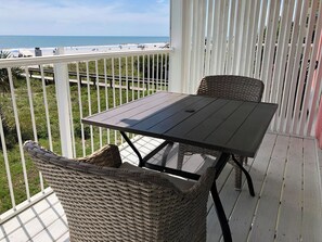 Un balcone con tavolo e sedie in vimini, vista sulla spiaggia.