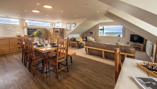 A spacious loft with a dining area, living room, and a large window overlooking the sea. - 4 Bed in Cresswell (oc-d42828) (Cresswell)
