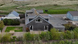 A coastal residential area with houses, a paved road, and a beach in the background. - 4 Bed in Cresswell (oc-d42828) (Cresswell)