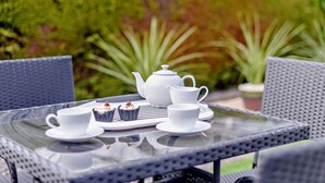 Une table en verre avec une théière blanche, deux tasses blanches et deux petits gâteaux.