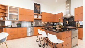 Une cuisine moderne avec des meubles en bois, des appareils en acier inoxydable et un îlot central doté de tabourets de bar.