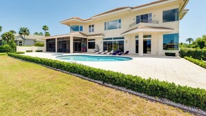 Une maison moderne à deux étages, dotée d’une piscine, d’un espace extérieur aménagé et d’une pelouse bien entretenue.