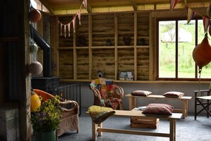 A rustic cabin interior with a fireplace, wicker furniture, and a view of the outdoors.