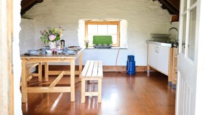 Une chambre mansardée au charme rustique, avec une table en bois, un banc et une fenêtre donnant sur un champ verdoyant.