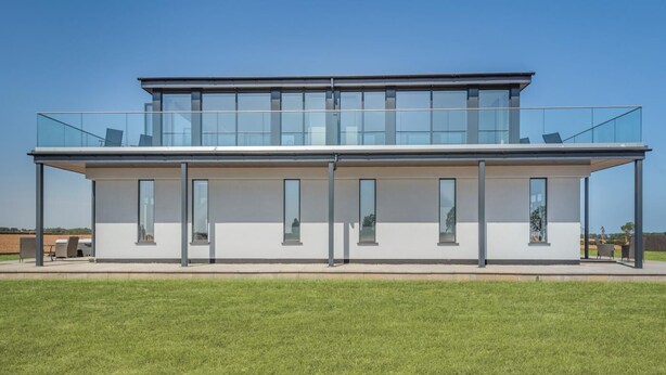 Ein modernes, zweistöckiges Gebäude mit großen Fenstern und einem Glasbalkon.