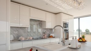 Eine moderne Küche mit weißen Schränken, einer Marmor-Spritzschutzwand und einem Edelstahl-Spülbecken.
