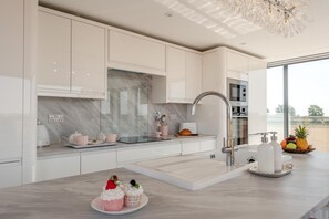 Eine moderne Küche mit weißen Schränken, einer Marmor-Spritzschutzwand und einem Edelstahl-Spülbecken.