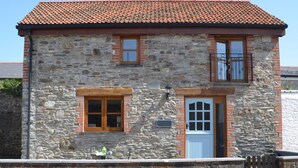 Ein Steinhaus mit rotem Ziegeldach, einer Holztür und einem kleinen Balkon.