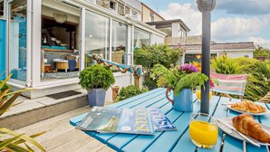 A seaside terrace with a table set for breakfast, featuring croissants, a glass of orange juice, and a magazine. - 2 Bed in Y Felinheli (oc-40860) (Y Felinheli)