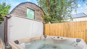 A hot tub with a wooden deck and a wooden fence in the background.