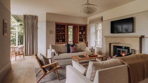 Ein Wohnzimmer mit Sofa, Sesseln, Couchtisch, Kamin und Fernseher.