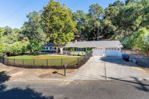 Ein Wohnhaus mit eingezäuntem Garten, Garage und gepflegtem Rasen.