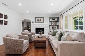A living room with a fireplace, a sofa, armchairs, and a coffee table. - Remodeled 4BR Retreat - FirePit + Basketball Court (Atascadero)