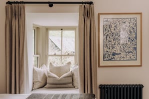 A bedroom with a large window, a radiator, and a framed abstract painting. - 2 Bed in Grasmere (oc-lr246) (Penrith)