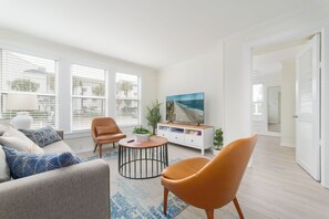 Ein Wohnzimmer mit einer Couch, zwei Sessel, einem Couchtisch, einem Fernseher und einer Pflanze.