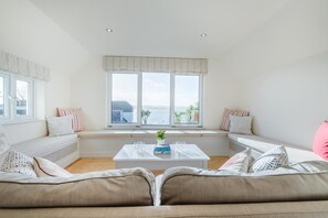A living room with a large window, a white coffee table, and a beige sofa. - 5 Bed in Rock (oc-u22448) (Rock)